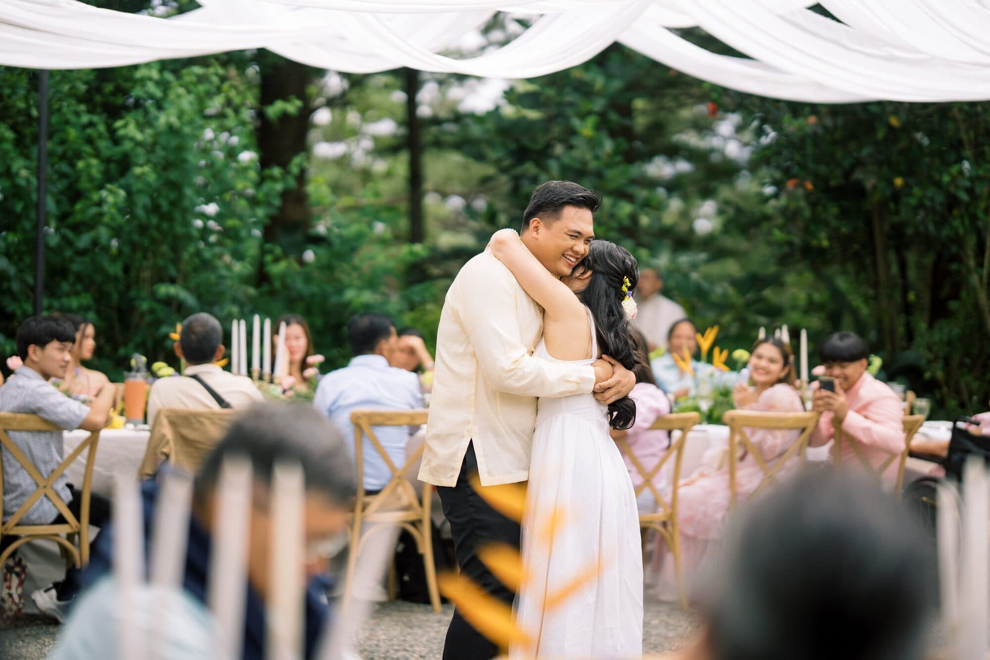 The groom holding the bride in a long hug during the reception as seated guests watch